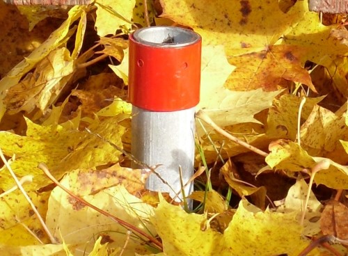 Photo of a red and white pipe in the ground that shows what a boundary marking might look like.