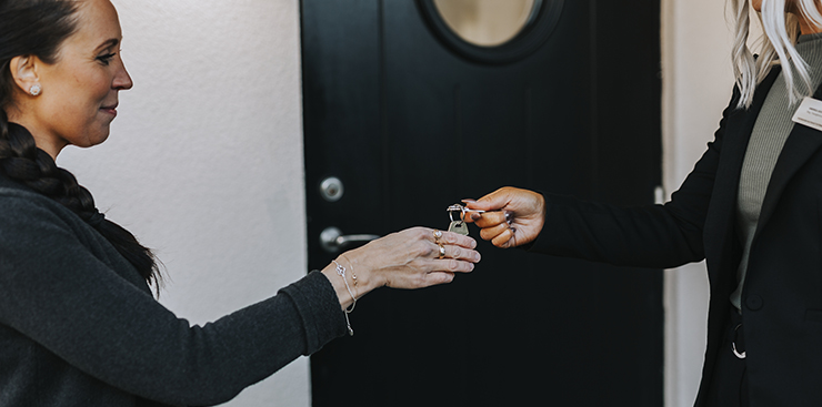Mäklare räcker över nyckel till kvinnlig köpare.